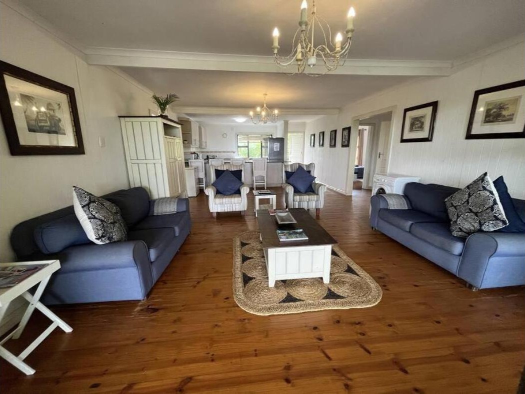 Soggiorno con pavimenti in legno e divani di Alfies House, casa con cucina nel complesso Campismo Ninho, Ponta Malongane, Mozambico