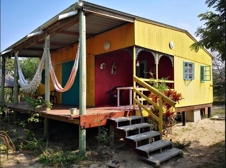 Farbenfrohes Holzchalet mit Hängematten auf der Veranda, Casa Machado, Macaneta, Distrikt Marracuene, Mosambik.
