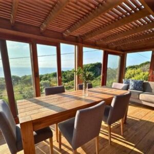 Обеденная и лаунж-зона с видом на море сквозь деревянные ставни в Honey's House, Ponta Mamoli, Мозамбик