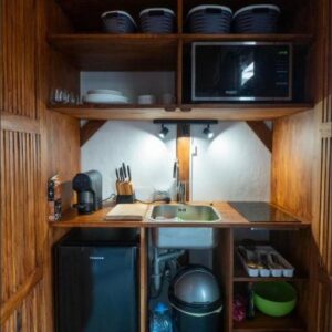 Índico Breeze自助式小屋的小厨房，配有木制橱柜，莫桑比克托福海滩托福市场后面