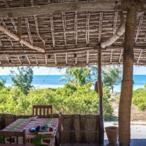 Веранда под соломенной крышей с обеденным столом и видом на море в Namahamade Lodge, Cabaceira Pequena