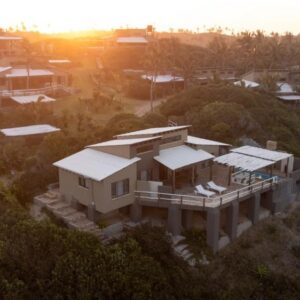 日落时分金贾塔湾沙丘上Paz do Pai Lodge建筑的鸟瞰图